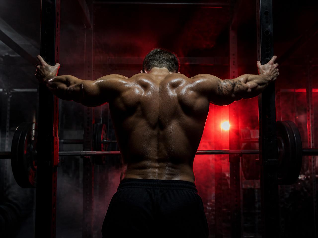 Muscular man training in a dark gym under red light